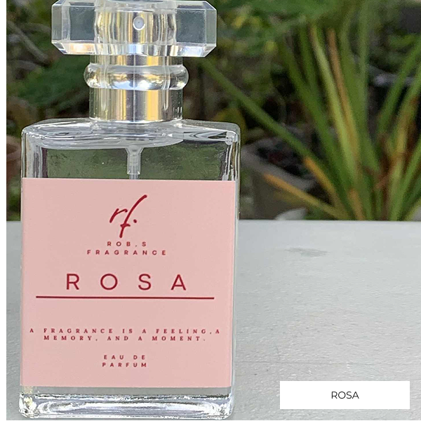 Perfume bottle labeled 'Rosa' with a pink label against a blurred green plant background